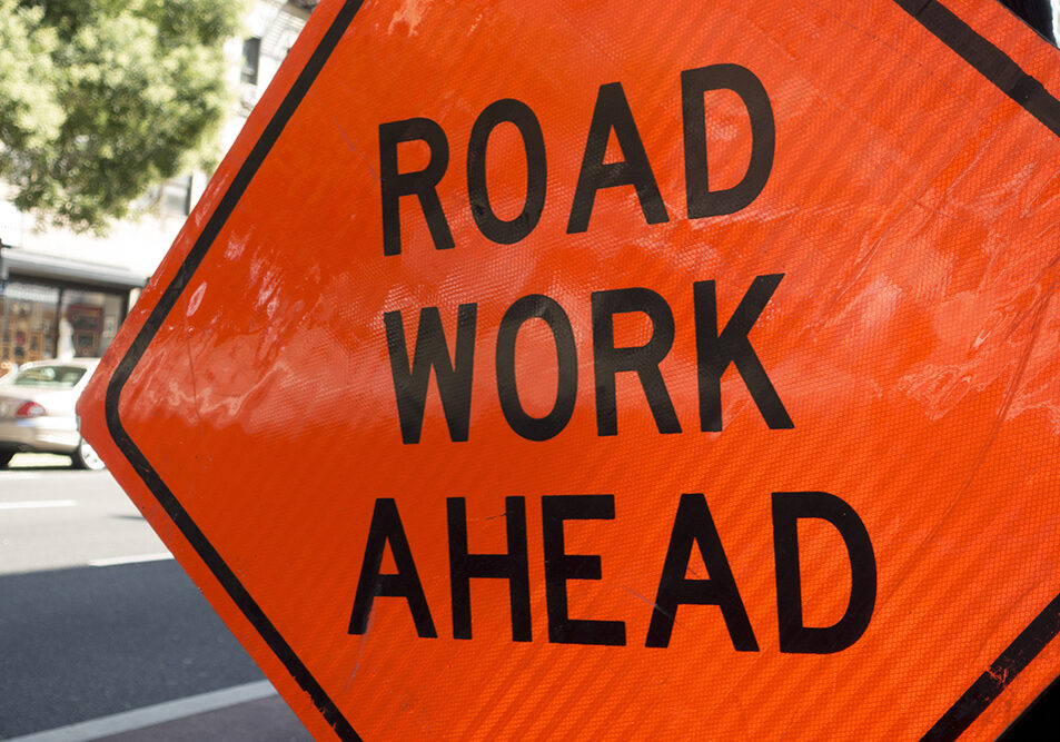 diamond shaped orange red reflector street sign that reads road